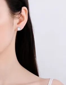Detail of s925 silver aurora moonstone stud earrings on female model in soft lighting