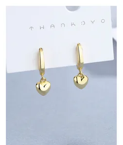 Gros plan détaillé de boucles d'oreilles cœur dorées avec finition polie sur support