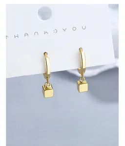 Detailed view of minimalist gold geometric cube drop earrings on jewelry display card