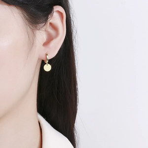Polished 925 sterling silver geometric disc hoop earrings worn by a model on white background