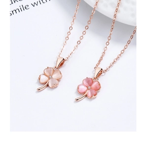 Detail of rose gold clover necklaces with pink opal hearts and central crystal