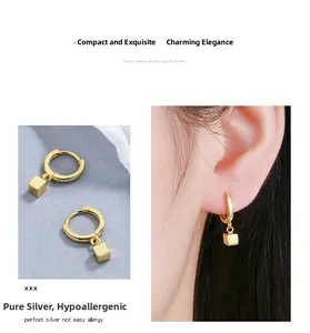 Detail view of gold cube drop earrings with model wearing minimalist S925 silver jewelry
