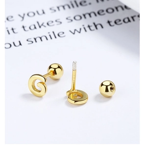 Close-up of golden letter G stud earrings with S925 silver screw ball backings