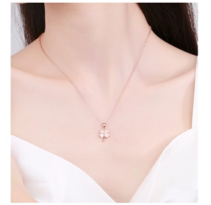 Detail of rose gold clover necklace with pink petals on a model's collarbone