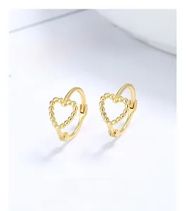 Macro shot of 925 silver hollow heart earrings with gold bead dots on white card