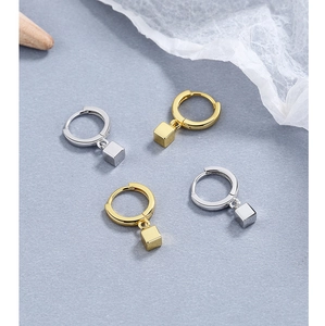 Detail of minimalist geometric square earrings in polished gold and silver finish