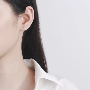 Minimalist S925 sterling silver LUCK letter stud earrings on a female model's ear
