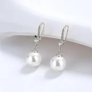 Close-up of elegant pearl drop earrings with sparkling pavé crystal silver hooks