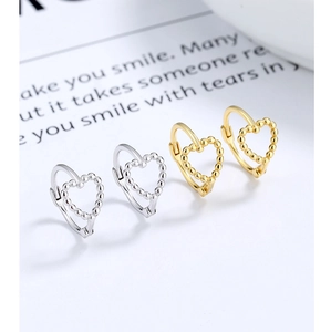 Macro shot of silver and gold heart hoop earrings with intricate beaded metal texture