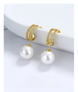Détail macro de boucles d'oreilles perles style français avec zircon sur socle blanc
