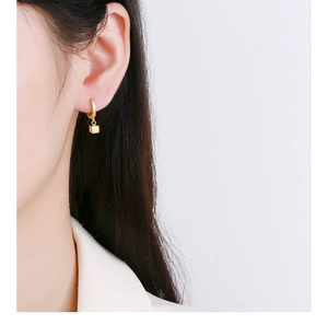 Close-up of minimalist gold square cube dangle earring on model ear in high detail