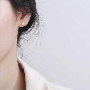 Minimalist 925 sterling silver golden letter N stud earrings shown on model ear