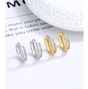 Detail of gold and silver double-row pave cubic zirconia hoop earrings on white background