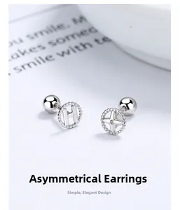 Macro view of asymmetrical 925 silver stud earrings with letter H and star motifs