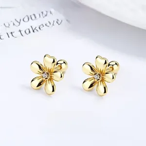 Macro detail of gold flower studs with zircon center and secure ball screw back closure