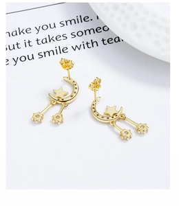 Close-up of gold moon and star tassel earrings with shimmering zircon accents