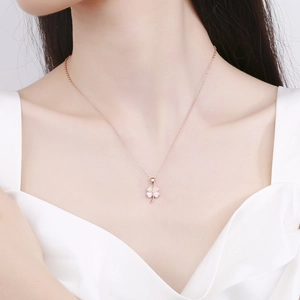 Rose gold four-leaf clover opal pendant necklace on female model at the collarbone