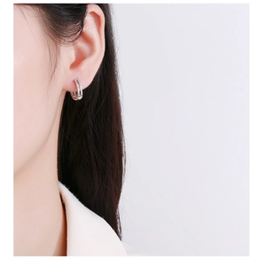 Detail of minimalist double-layered silver hoop earrings with pavé zircons on model ear