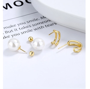 Détail de boucles d'oreilles en perles et anneaux en C dorés sertis de cristaux brillants