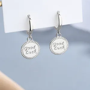 925 silver coin earrings featuring Good Luck engraving and textured edge on blue background