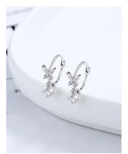 Macro shot of S925 sterling silver bow earrings with zircon tassels on a white tray
