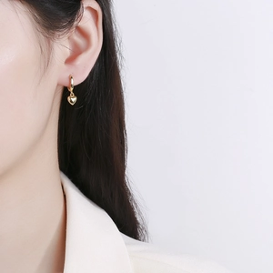 Boucles d'oreilles cœur en argent 925 doré élégantes portées par un mannequin
