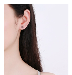 Close-up of 925 silver round stud earring featuring H letter design with micro pavé crystals