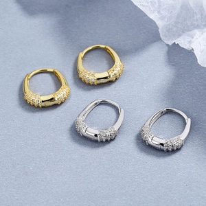 Macro shot of U-shaped hoop earrings with gold and silver finishes and pavé-set zircons