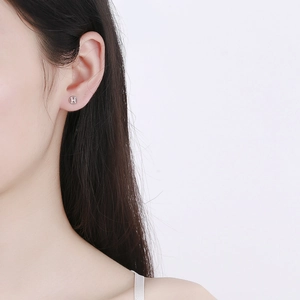 Sterling silver round earring with H logo cut-out worn by model on white background