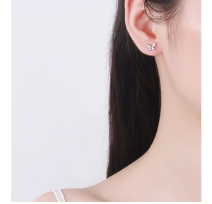 Close-up of pink enamel butterfly stud earrings worn on a model's ear, S925 silver