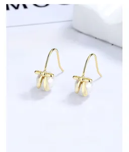 Detailed view of elegant bow-knot pearl earrings featuring polished gold metal finish