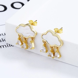 Detail of cloud-shaped gold earrings with white inlay and sparkling teardrop crystals