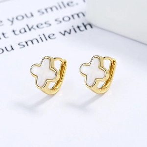Détail de boucles d'oreilles trèfle avec nacre blanche sur métal doré poli brillant