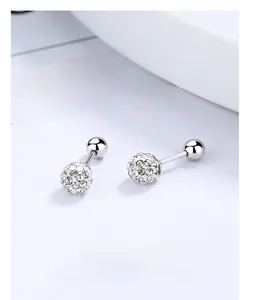 Détail macro de boucles d'oreilles boules en argent 925 avec cristaux rouges sur plateau