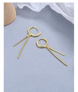 Detail of elegant gold tassel earrings with polished bars and fine beaded chains