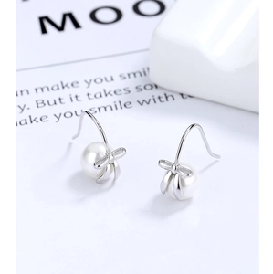 Close-up of elegant bow pearl drop earrings with polished silver finish and glossy pearls