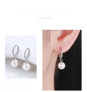 Detailed view of silver drop earrings with white pearls and sparkling rhinestone accents