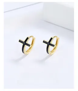 Vue macro de boucles d'oreilles créoles en argent 925 dorées avec croix en émail noir