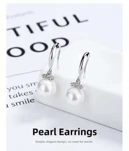Gros plan sur les boucles d'oreilles pendantes en argent 925 avec perles et zirconiums