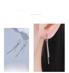 Macro detail of long silver tassel earrings showing sleek bead chains and straight bars