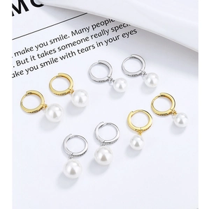 Macro detail of gold and silver hoop earrings with round white pearls and pavé zircons