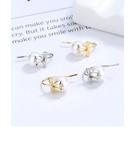 Macro detail of bow-knot pearl drop earrings in gold and silver finish options