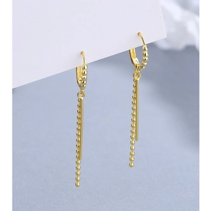 Detail of gold dangle earrings with polished bar and beaded chain on card