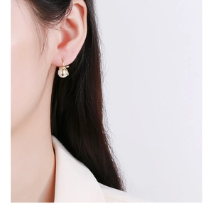Close-up of golden bow pearl earring on model showcasing elegant jewelry craftsmanship