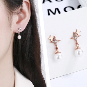 Detailed view of silver and rose gold star earrings with pearls and zircon inlay