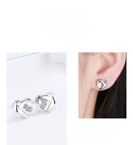 Détail de boucles d'oreilles cœur en argent 925 avec zircons portées sur l'oreille