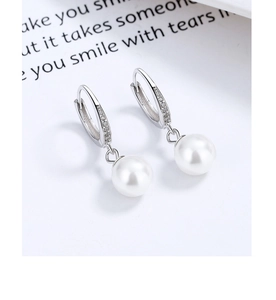 Close-up of pearl drop earrings with silver pavé hoops on a poetic background card
