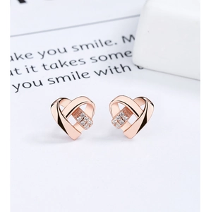 Vue macro des boucles d'oreilles cœur en or rose avec détails en zircon scintillant
