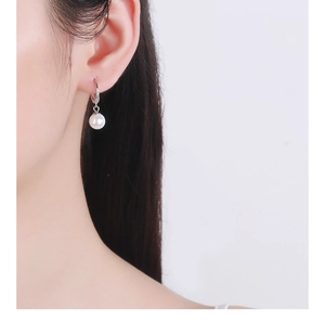 Close-up of minimalist teardrop pearl earrings worn with silver cubic zirconia hook