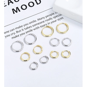 Various sizes of minimalist silver and gold hoop earrings set on white background